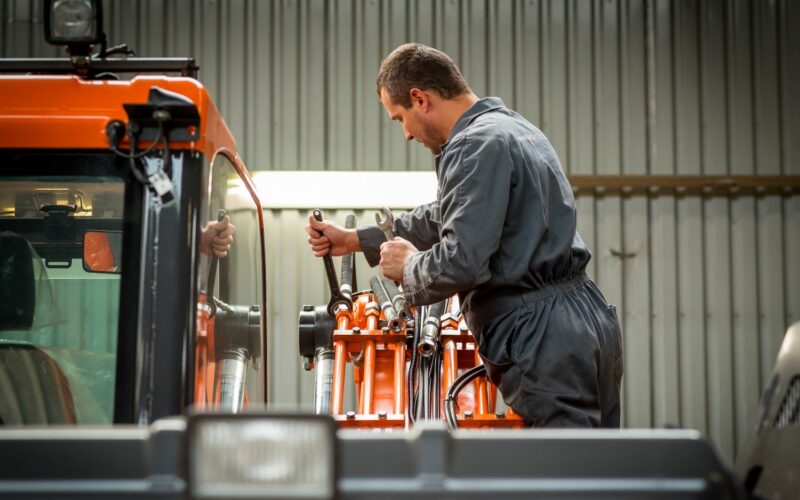 The factory worker is actively involved in manufacturing a vehicle.
